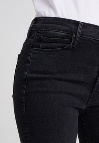 Black denim jeans with a high waist, featuring subtle stitching details, two front pockets, and a classic five-pocket design.