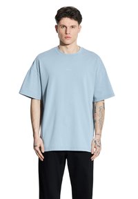 Jasnoniebieska bawełniana koszulka z luźnym krojem, kr ótkimi rękawami i okrągłym dekoltem. Posiada małe logo nadrukowane na klatce piersiowej.
