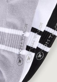 Drei Paar Sportsocken in einer Mischung aus Grau, Weiß und Schwarz, mit gerippter Textur und kontrastierenden Streifen. Akzentuiert mit gedruckten Logos.
