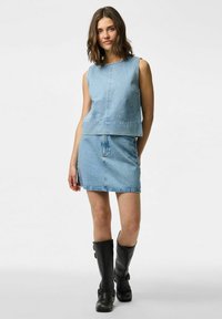 Set od svjetloplavog traper bez rukava i suknje, s raspršenim ukrasima. Uparen s crnim čizmama do koljena.