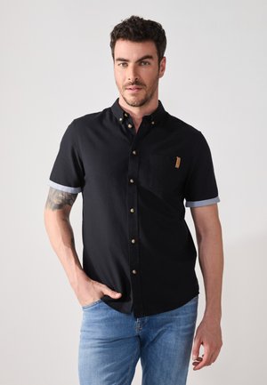 Short-sleeve black button-up shirt with a blue cuff, a chest pocket, and gold-tone buttons. Fabric has a smooth texture.
