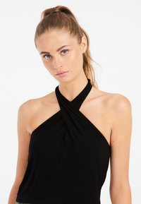 Top negro sin mangas con escote retorcido. Tela suave y elástica con silueta ajustada. Estilo simple y minimalista.