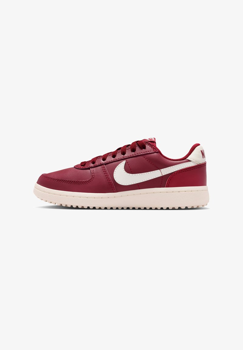 Nike-sneakers van rood leer met witte accenten, voorzien van een ronde neus, veters aan de voorkant en een gestructureerde buitenzool voor grip.