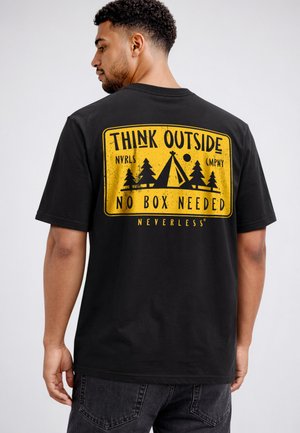 Man wearing black t-shirt with yellow camping design and text "Think outside, no box needed" on the back.
