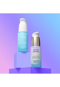 To skincare flasker på en lavendel pedestal. Den venstre flaske er lyseblå med en hvid pumpe, mærket "TIDAL." Den højre flaske er lilla med en sølvhætte, mærket "GOOD GENES."