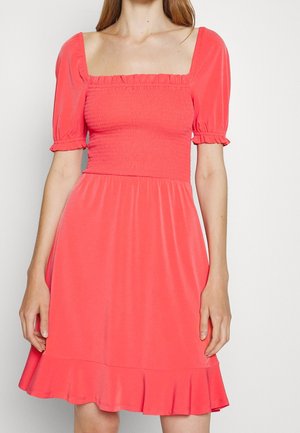 Korallrosa klänning med fyrkantig halsringning, smockad bodice och puffärmar. Har en utsvängd kjol med volangkant. Slät tygtextur.