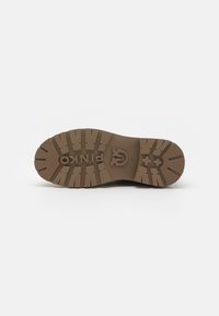 Donkerbruine rubberen schoenzool met een gegroefd loopvlak, voorzien van een logo in het midden en een gestructureerd oppervlak voor grip.