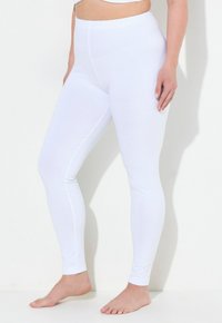 Bílé legíny z měkké, elastické látky. Mají široký elastický pas a úzký střih, sahají až na kotník. Hladká textura.