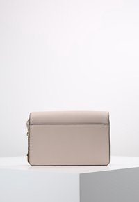 Borsa a mano beige chiaro con una texture liscia, forma rettangolare, chiusura a pattina e dettagli in metallo dorato sul lato.