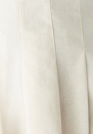 Svetlo béžová plisovaná látka s textúrovaným povrchom a jemnými škvrnami. Dizajn je jednoduchý a štruktúrovaný, s dôrazom na čisté línie.