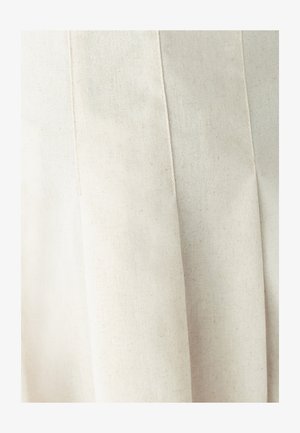 Svetlo béžová plisovaná látka s textúrovaným povrchom a jemnými škvrnami. Dizajn je jednoduchý a štruktúrovaný, s dôrazom na čisté línie.