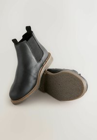 Czarne skórzane buty Chelsea z elastycznymi bocznymi panelami, zaokrąglonym noskiem i teksturowaną gumową podeszwą z kontrastującą jasnobrązową lamówką.