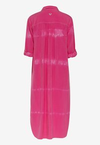 Pink tie-dye dress with a buttoned collar, long sleeves rolled up, and a gathered back pleat. Features a small logo on the back.