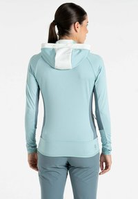 Helles blaues langärmeliges Sportoberteil mit einer kontrastierenden weißen Kapuze, glatter Textur und tailliertem Design. Enthält Akzentnähte und Daumenlöcher.