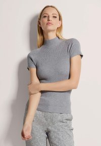 Grijze geribbelde top met korte mouwen, hoge hals, aansluitend ontwerp en zachte textuur, gecombineerd met gestreepte grijze broek.