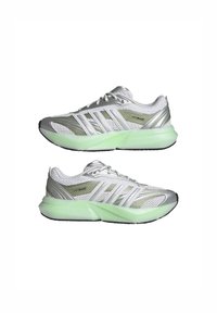 White athletic shoes with silver accents, mesh upper, green translucent midsole, and black rubber outsole. Features three stripe logo design.