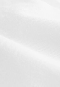 Tissu blanc à texture lisse, présentant un léger éclat et un motif de tissage diagonal, créant des ombres subtiles sur toute la surface.