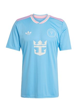 Light blue soccer jersey with pink stripes on shoulders, white crown logo in center, Adidas logo on right chest, and "Miami" team crest on left chest.