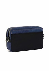 Pochette in denim e pelle nera con zip doppie, forma rettangolare e appendici in argento, caratterizzata da una superficie liscia e priva di motivi.