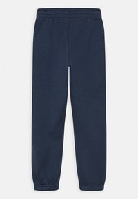 Navy urheilu-housut, jotka on valmistettu pehmeästä kankaasta. Niissä on joustava vyötärö ja kootut hihnat nilkoissa mukavan istuvuuden takaamiseksi.