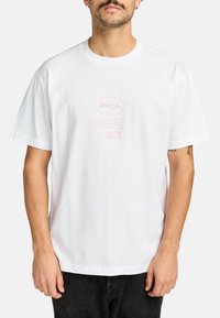 White cotton t-shirt with short sleeves, featuring a large pink graphic print stating "RVCA Balance of Opposites" on the front.