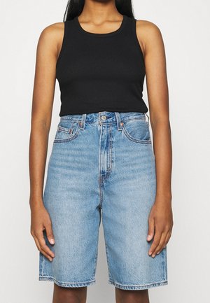 Débardeur côtelé noir associé à un short en denim bleu clair taille haute. Le short est doté d'une fermeture à bouton et d'un design classique à cinq poches.