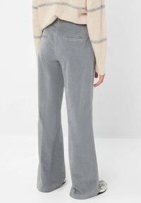 Grijze corduroy wijde pijpen broek met een zachte textuur, voorzien van achterzakken en subtiele stikdetails, gecombineerd met een lichtgekleurde trui.