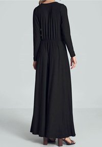 Svart långärmad klänning med sammanknippad midja, flödande kjol och slät textur, med rund halsringning och minimalistisk design.