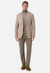Beige geruite blazer met twee knopen, grijze coltrui, kaki broek en bruine suède schoenen. Getailleerde pasvorm en gestructureerde stoffen.