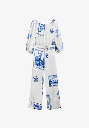 Fehér overall kék virág- és képeslapmintákkal, hosszú puffos ujjak, szabott derék és megkötős öv részlet jellemzi. Puha anyagtextúra.