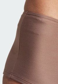 Hnědé plavkové kalhotky s vysokým pasem, hladkým povrchem, elastickým pasem a plochými švy, které vyzdvihují minimalistický design.