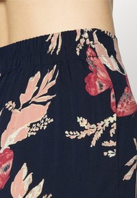 Blommönstrad tyg med rosa och röda blommor på en marinblå bakgrund. Design med elastisk midja i mjukt, lätt material.