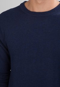 Granatowy sweter dziany z okrągłym dekoltem i długimi rękawami, charakteryzujący się miękką fakturą i prostym, czystym designem.