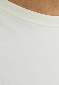 Ljusgrön bomulls T-shirt med ribbad rundhals och slät textur, som visar sömnadsdetaljer längs kragen.