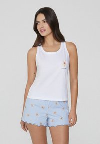 Camiseta sin mangas blanca con un gráfico de un oso y el texto "dulce osito", combinada con pantalones cortos a rayas azules que presentan motivos de osos dispersos y bordes en forma de concha.