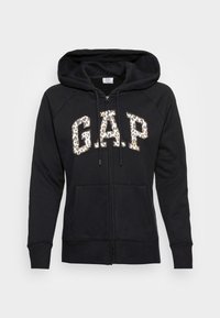 Felpa nera con zip, logo "GAP" in stampa leopardata, tasche frontali e cappuccio con cordino, esposta su uno sfondo semplice.