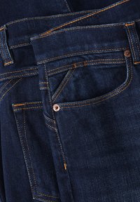 Dark blue denim jeans with orange stitching, featuring multiple pockets, a metal button accent, and a smooth texture.