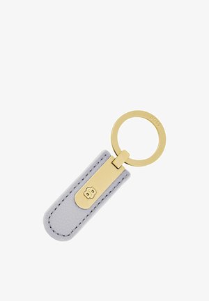 Porte-clés en métal doré attaché à une étiquette en cuir gris avec des bords cousus et un logo embossé.