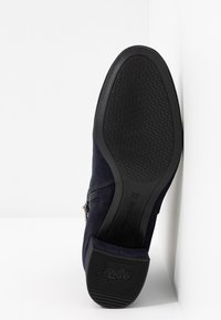 Semelle de chaussure bleu foncé avec une semelle extérieure en caoutchouc texturée et un talon marqué "ANTI SLIDE" et taille 37, présenté sur fond blanc.