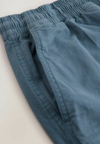 Pantalones cortos de algodón azules con cinturilla elástica, que presentan bolsillos laterales y una textura suave, capturados desde un ángulo cercano.