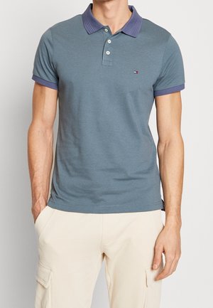 Poloshirt aus blauem Stoff mit dunkelblauem Kragen und Ärmeln. Verfügt über ein kleines Logo auf der Brust. Strukturierte Baumwolle mit lässigem Schnitt.