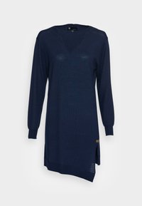 Robe tricotée marine à manches longues, col côtelé, fentes latérales et finition texturée. Présente une petite étiquette logo près de l'ourlet.