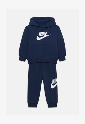 Sötétkék pamut melegítő, kapucnis pulóverrel és hozzáillő nadrággal. Mindkét darabon fehér Nike logó részletek találhatók; puha tapintású.