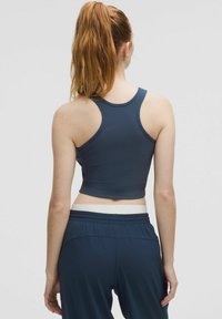 Donkerblauw geribbeld tanktop met een cropped pasvorm en racerback-ontwerp. Gepaard met bijpassende hoge taillebroek met een witte tailleband.