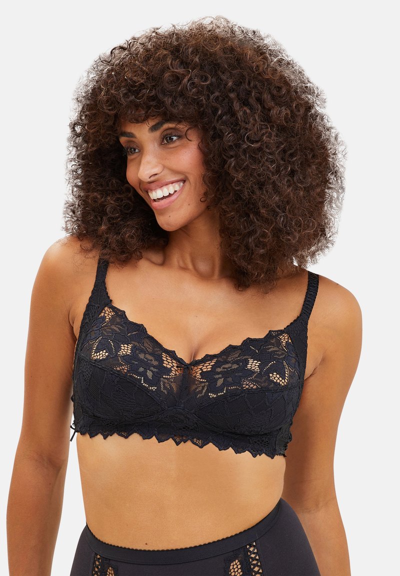 Zwarte kanten bralette met bloemenpatronen, geschulpte randen en verstelbare bandjes, met een doorschijnend paneel aan de voorkant.