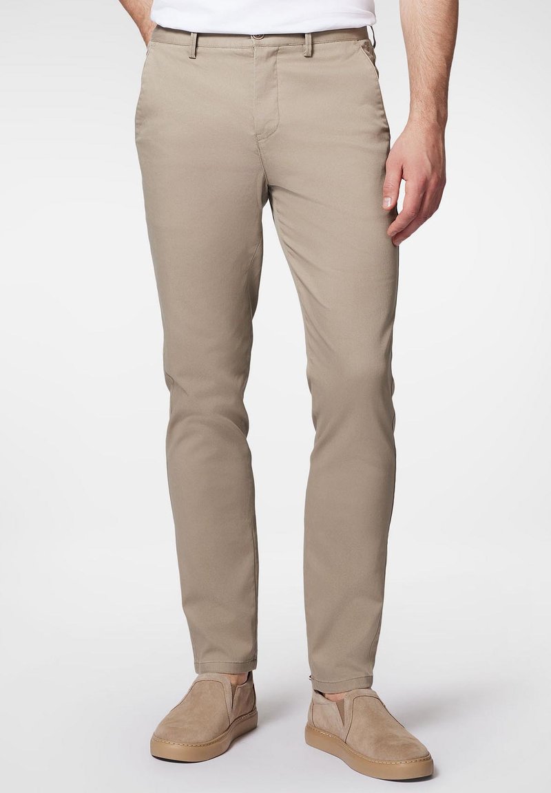 Beżowe chinosy wykonane z tkaniny żakardowej, w slim fit, z przednimi kieszeniami i zapięciem na zamek. Połączone z jasnobeżowymi butami typu slip-on.