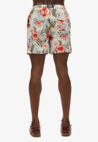 Bloemenshorts met een lichtblauwe achtergrond, levendige rode bloemen en groene bladeren; ontworpen met een achterzak en een elastische tailleband.