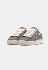 Sneaker in suede viola con lacci crema, dotati di una suola bianca testurizzata e intricate fantasie animali lungo i lati.