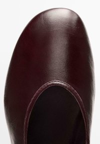 Bordeauxrode leren schoen met een afgeronde neus en een gladde textuur. Heeft een brede opening en subtiele stiksels langs de rand.