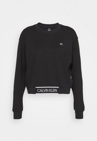 Sweatshirt noir court en coton, avec un col rond, des manches longues, et le logo blanc "CALVIN KLEIN" sur la bande à la taille.